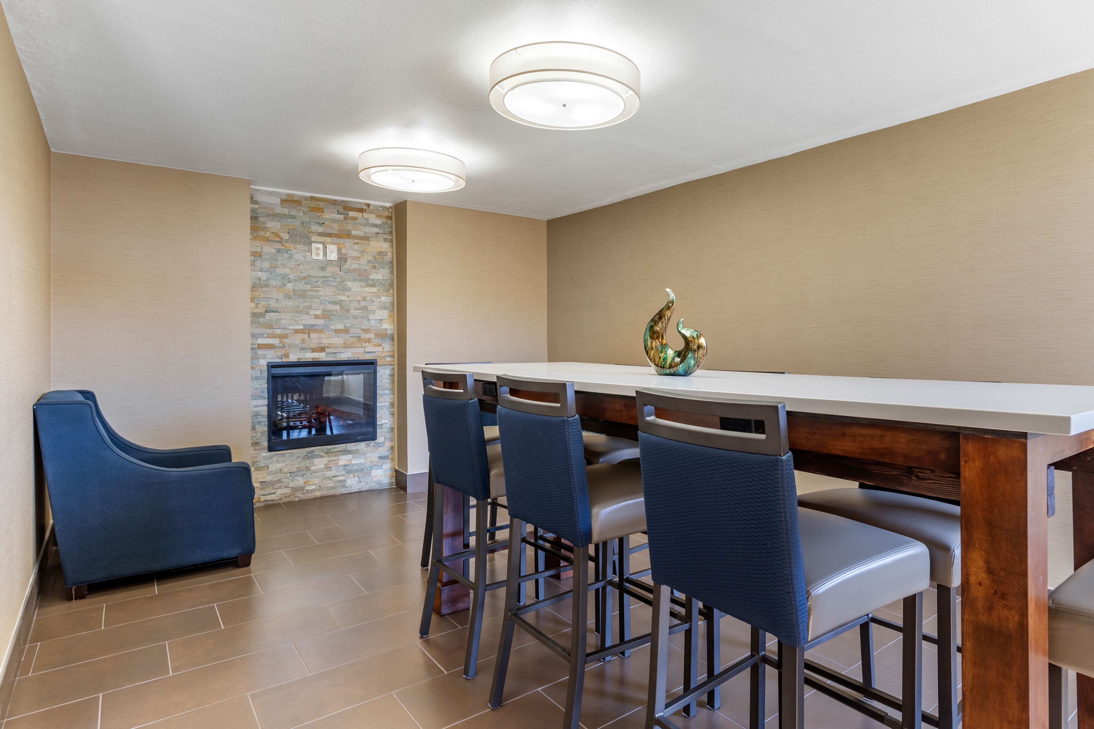 A modern kitchen with a stone backsplash, a bar area with stools, and a blue sofa.