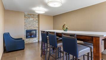 A modern kitchen with a stone backsplash, a bar area with stools, and a blue sofa.