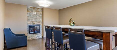A modern kitchen with a stone backsplash, a bar area with stools, and a blue sofa.