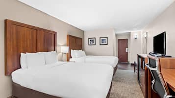 A hotel room with two beds, a desk, a chair, a TV, and two framed pictures on the wall.