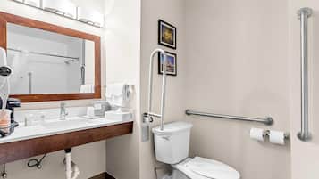 A modern bathroom with a sink, mirror, toilet, and handrails.