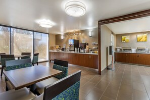 A modern restaurant with a dining area featuring booths and a counter with various food items.