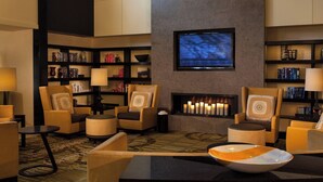 A modern lounge area with comfortable seating, a fireplace, and a television mounted on the wall.