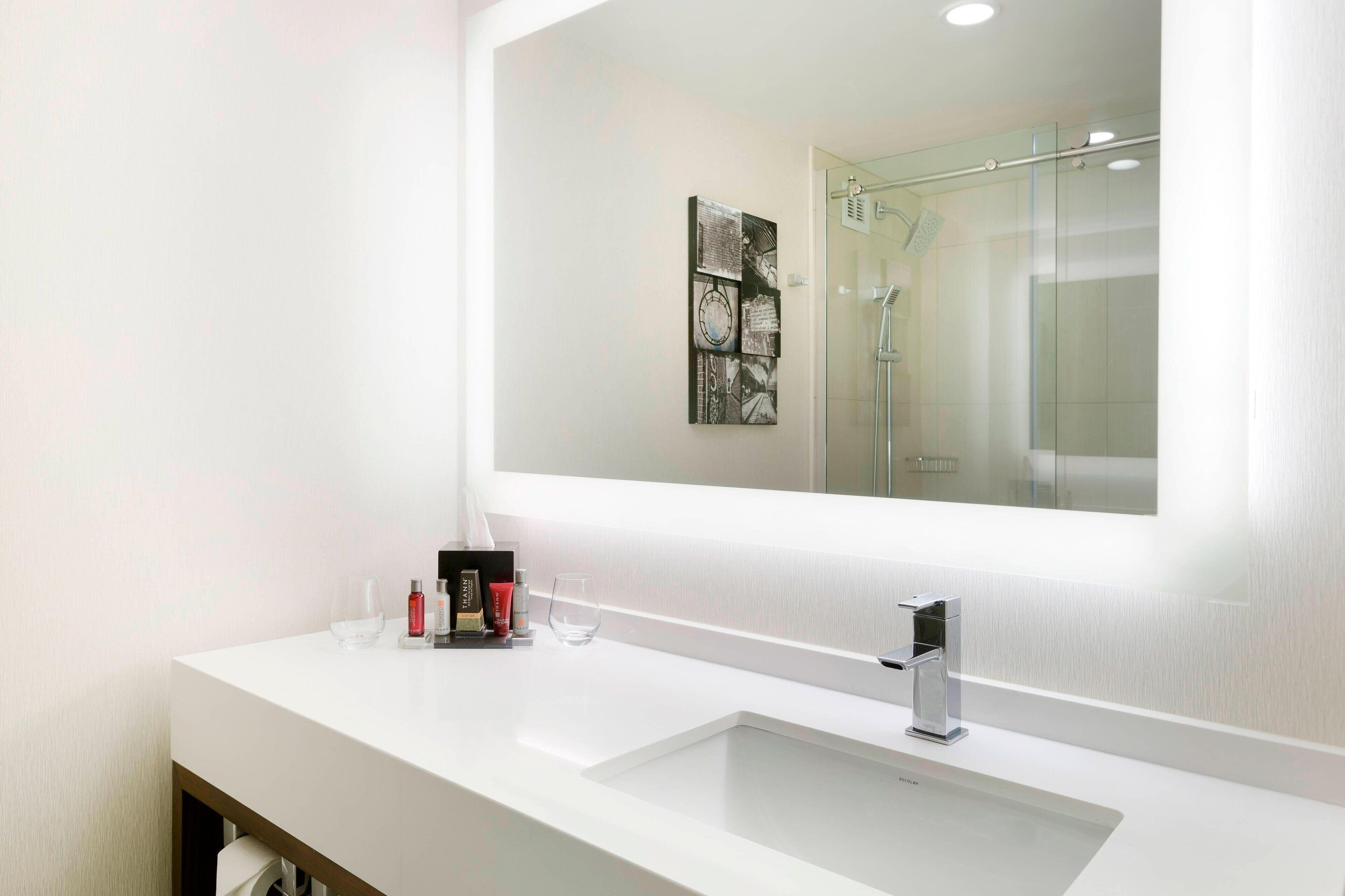 A modern bathroom with a white sink, a large mirror, and a glass shower enclosure.