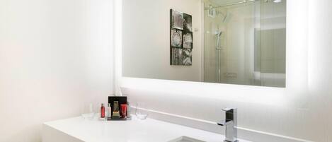 A modern bathroom with a white sink, a large mirror, and a glass shower enclosure.