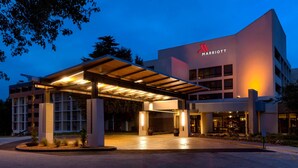 A Marriott hotel entrance with a covered walkway, a brick building, and a landscaped area with plants.