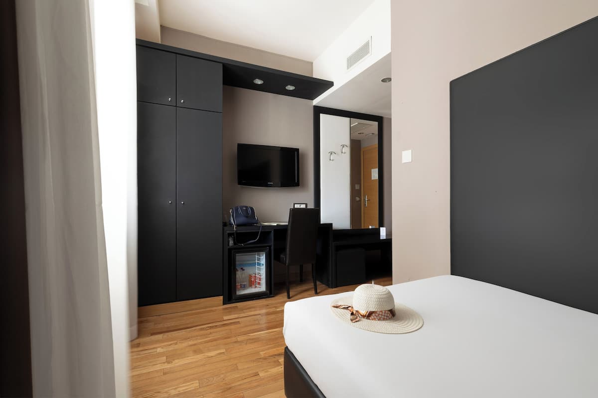 Une chambre d’hôtel comprenant un lit, un bureau avec une chaise, une télévision et une armoire.