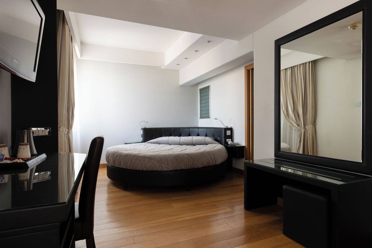 Une chambre moderne avec un grand lit, un bureau et un grand miroir.