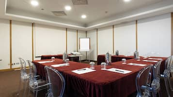 A conference room with a red tablecloth, clear plastic chairs, and a projector screen.