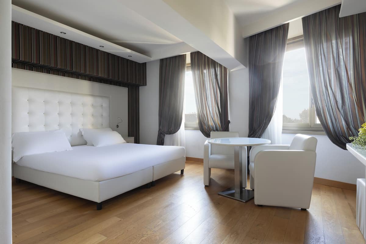 Une chambre d’hôtel moderne avec un grand lit, une petite table ronde et deux chaises.
