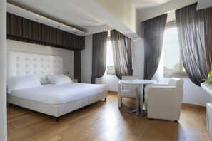 A modern hotel room with a large bed, a small round table, and two chairs.