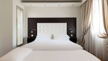 Une chambre d’hôtel moderne avec un grand lit, une tête de lit sombre, des tables de chevet avec des lampes et une grande fenêtre avec des rideaux.