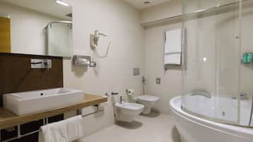 Un baño moderno con una bañera grande, un lavamanos separado, un bidé y una ducha con cerramiento de vidrio.