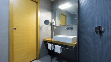 Une salle de bain moderne avec une porte en bois, un lavabo blanc, un miroir et un mur recouvert de carreaux bleus.
