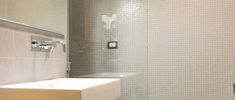Un baño moderno con un espejo grande, un lavabo y una zona de ducha.