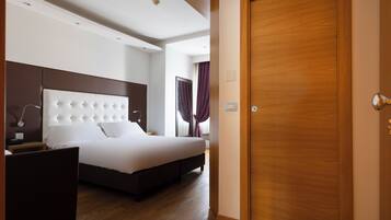 Una camera d'hotel moderna con un letto grande, una testiera in legno, un comodino e una porta in legno.