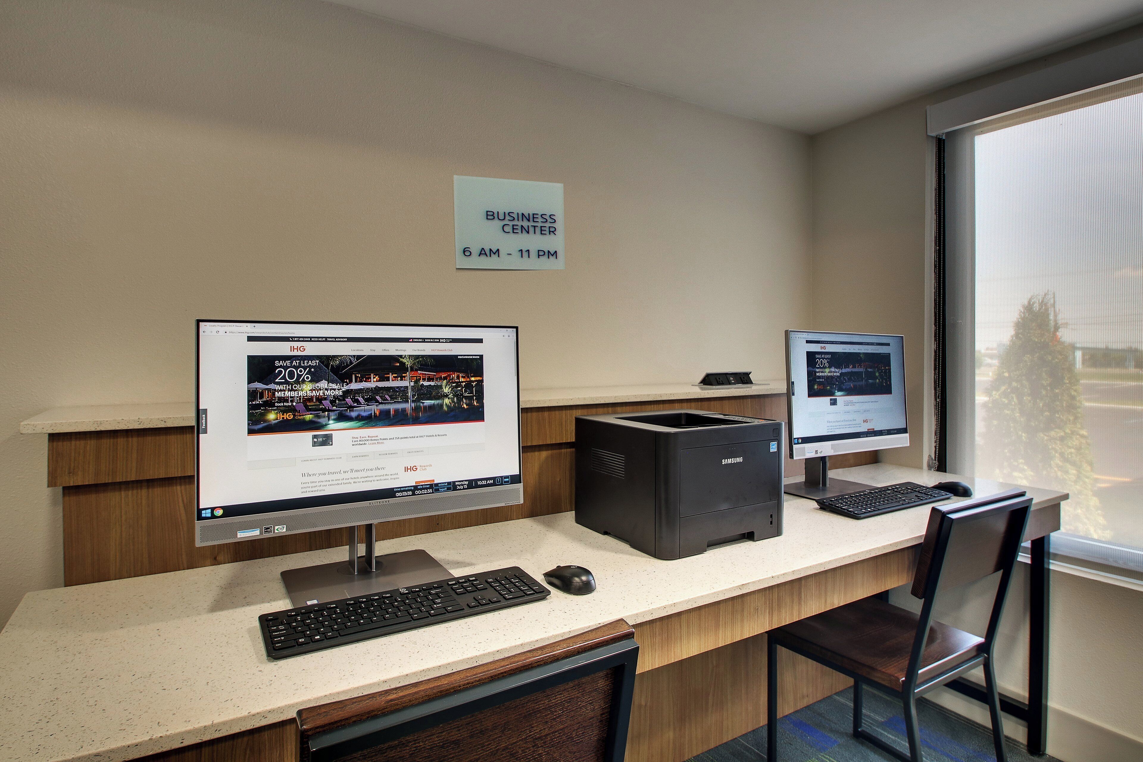 Un centro de negocios con dos monitores de ordenador, un teclado e impresora sobre un escritorio.