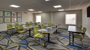 A conference room with tables and chairs, framed artwork on the walls, and large windows.