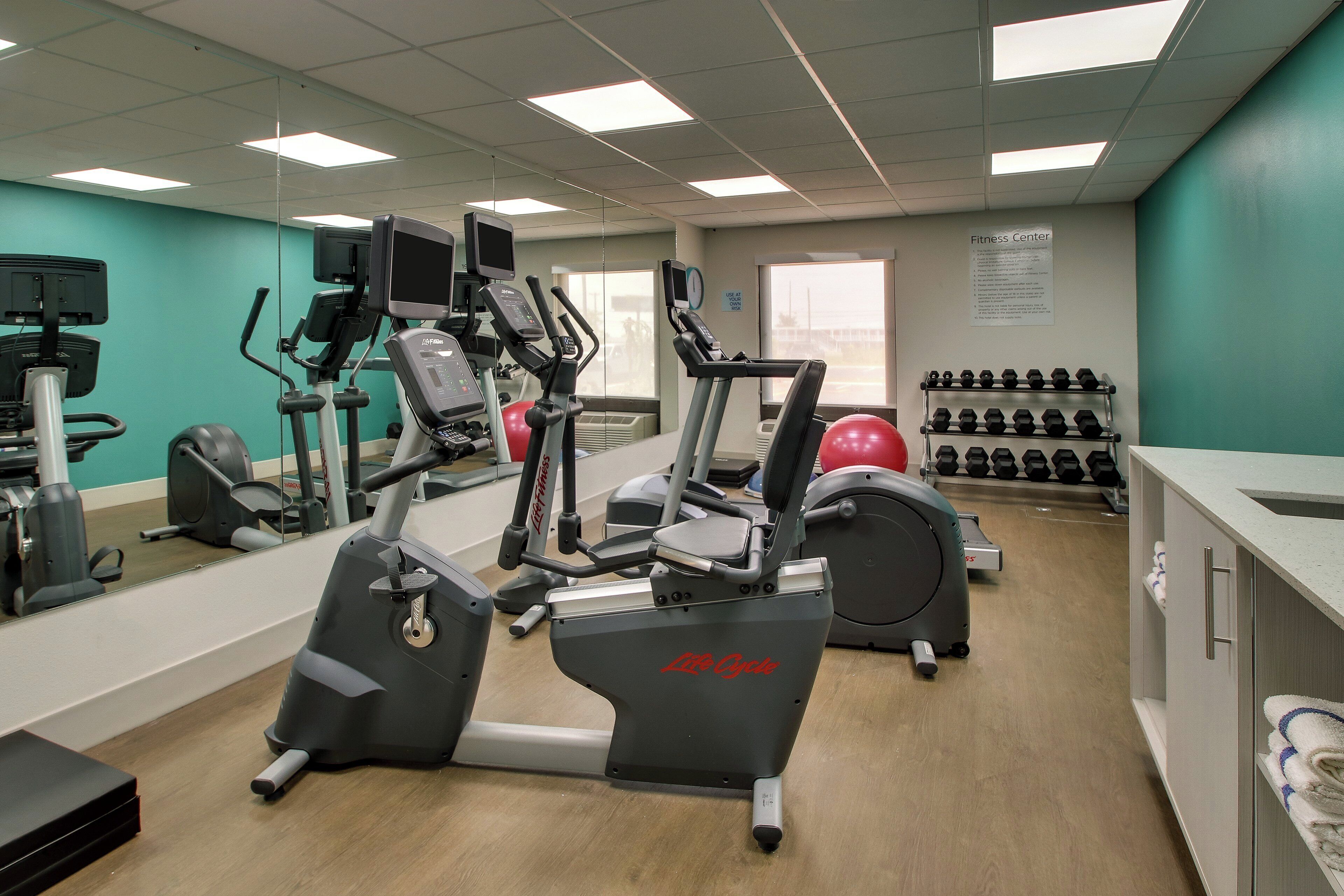 A fitness center with treadmills, elliptical machines, and a variety of weights.