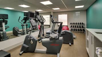 A fitness center with treadmills, elliptical machines, and a variety of weights.