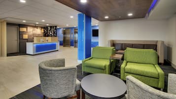 A hotel lobby with a reception desk, seating area, and elevators.