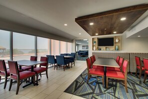 A hotel dining area with tables and chairs, a patterned carpet, and a large window. - Holiday Inn Express Atlantic City W Pleasantville by IHG (Pleasantville)