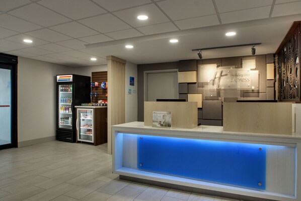 A hotel reception area with a reception desk, a refrigerator with beverages, and a wall-mounted sign for the Holiday Inn Express. - Holiday Inn Express Atlantic City W Pleasantville by IHG (Pleasantville)