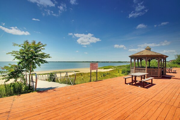 Una terraza de madera con un mirador, mesas de picnic y vista al mar.