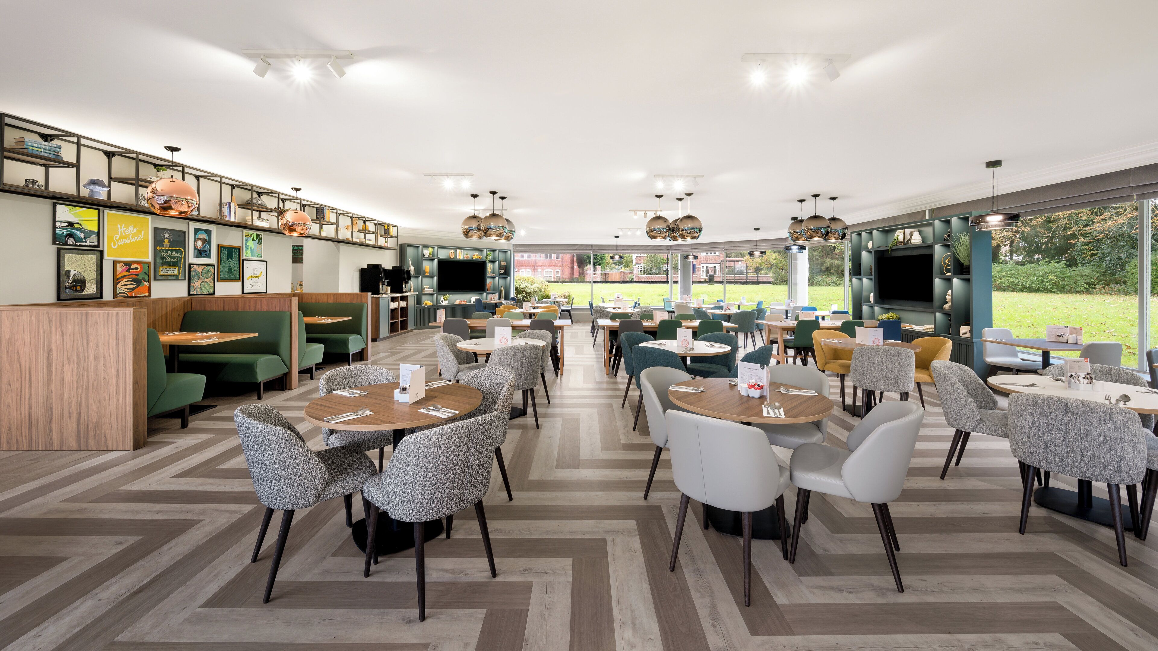 A spacious indoor dining area with multiple seating options, including booths and tables, and a large window offering a view of the outdoors.
