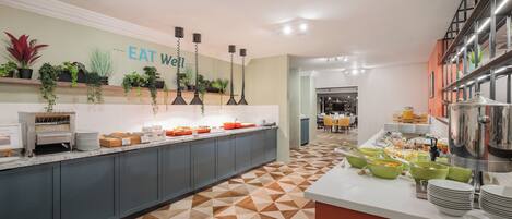 A modern kitchen with a geometric patterned floor, a buffet setup, and a sign that reads "EAT WELL".