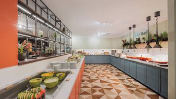 A modern buffet with a geometric patterned floor, a variety of food items, and a 'EAT Well' sign on the wall.