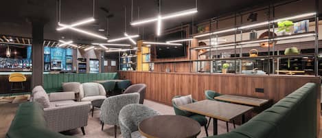 A modern bar area with green seating, wooden accents, and pendant lighting.