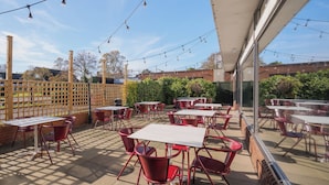 An outdoor patio with tables and chairs, string lights, and a view of the surrounding area. - Holiday Inn York by IHG (York)
