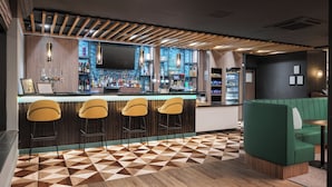 A bar area with wooden slats, a patterned floor, and a green booth. - Holiday Inn York by IHG (York)
