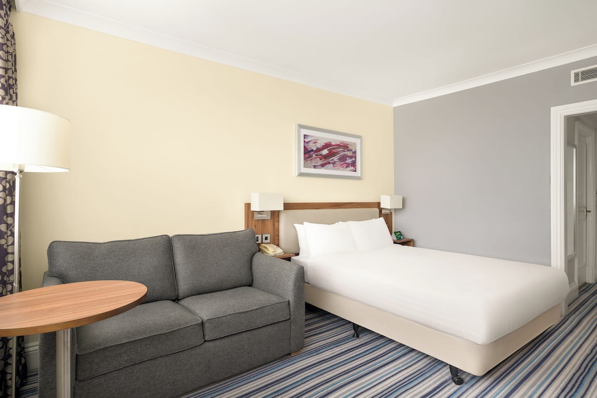 Ein Hotelzimmer mit Bett, einer Couch, einem kleinen Tisch und einem Bild an der Wand.