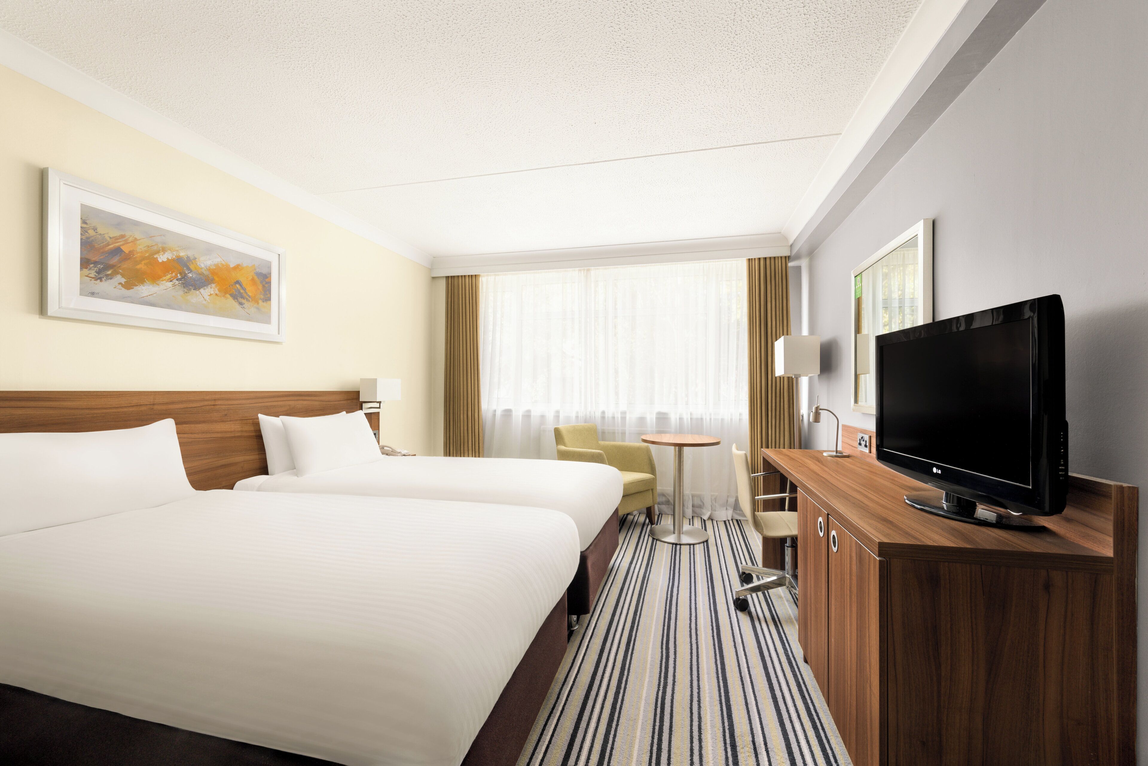 Een hotelkamer met twee bedden, een televisie, een bureau en een stoel.