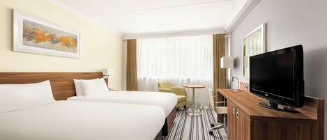 Een hotelkamer met twee bedden, een televisie, een bureau en een stoel.
