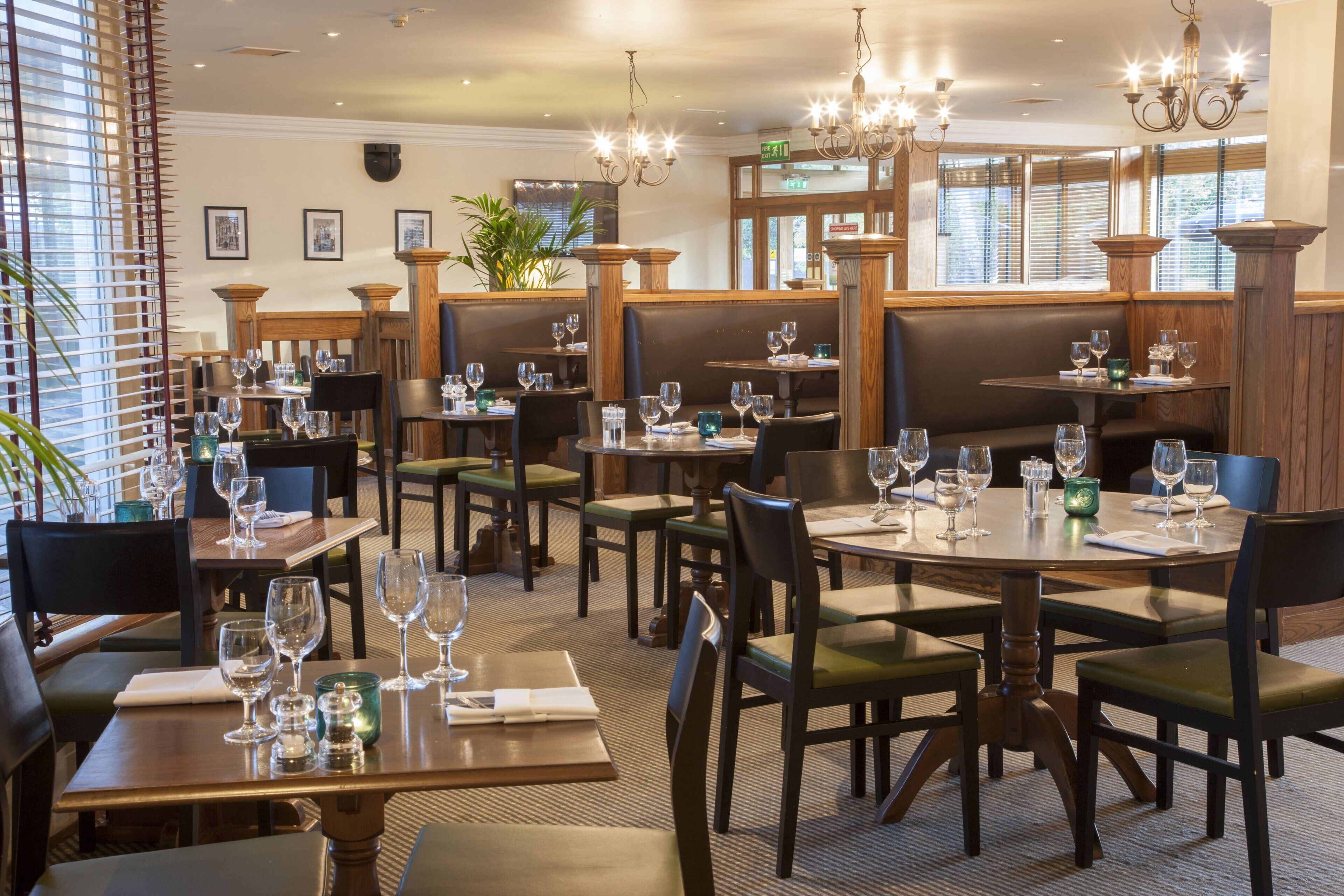 Interior de restaurante com várias mesas, cadeiras e lustres pendurados.