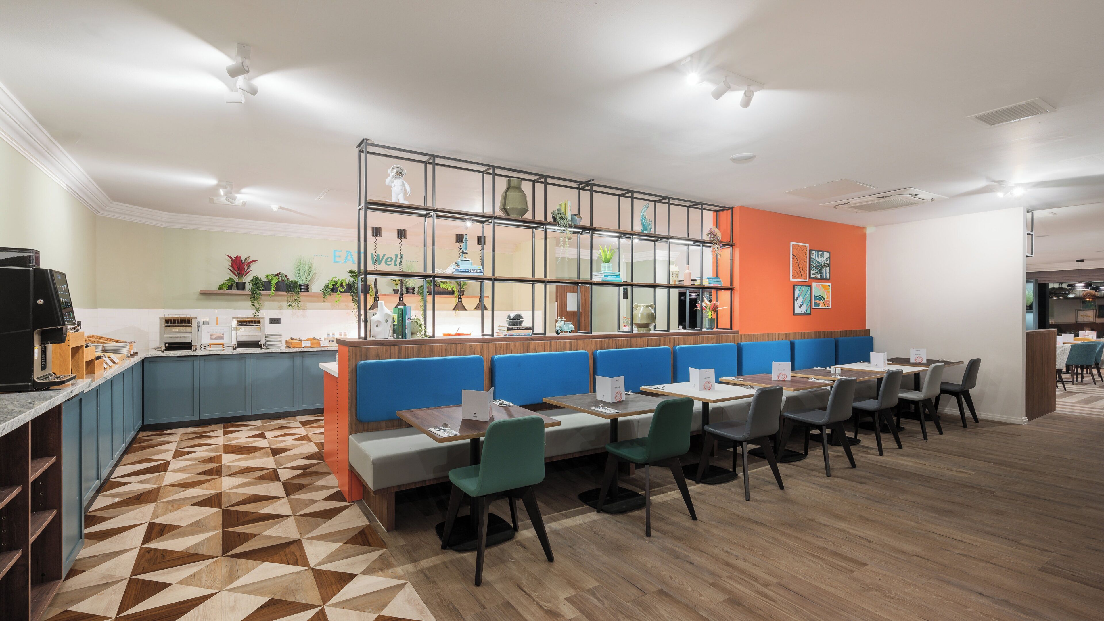 Un restaurante moderno con una zona de bar, mesas y sillas, y una cocina visible al fondo.