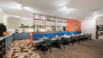 Een modern restaurant met een bar, zitplaatsen en een zichtbare keuken op de achtergrond.