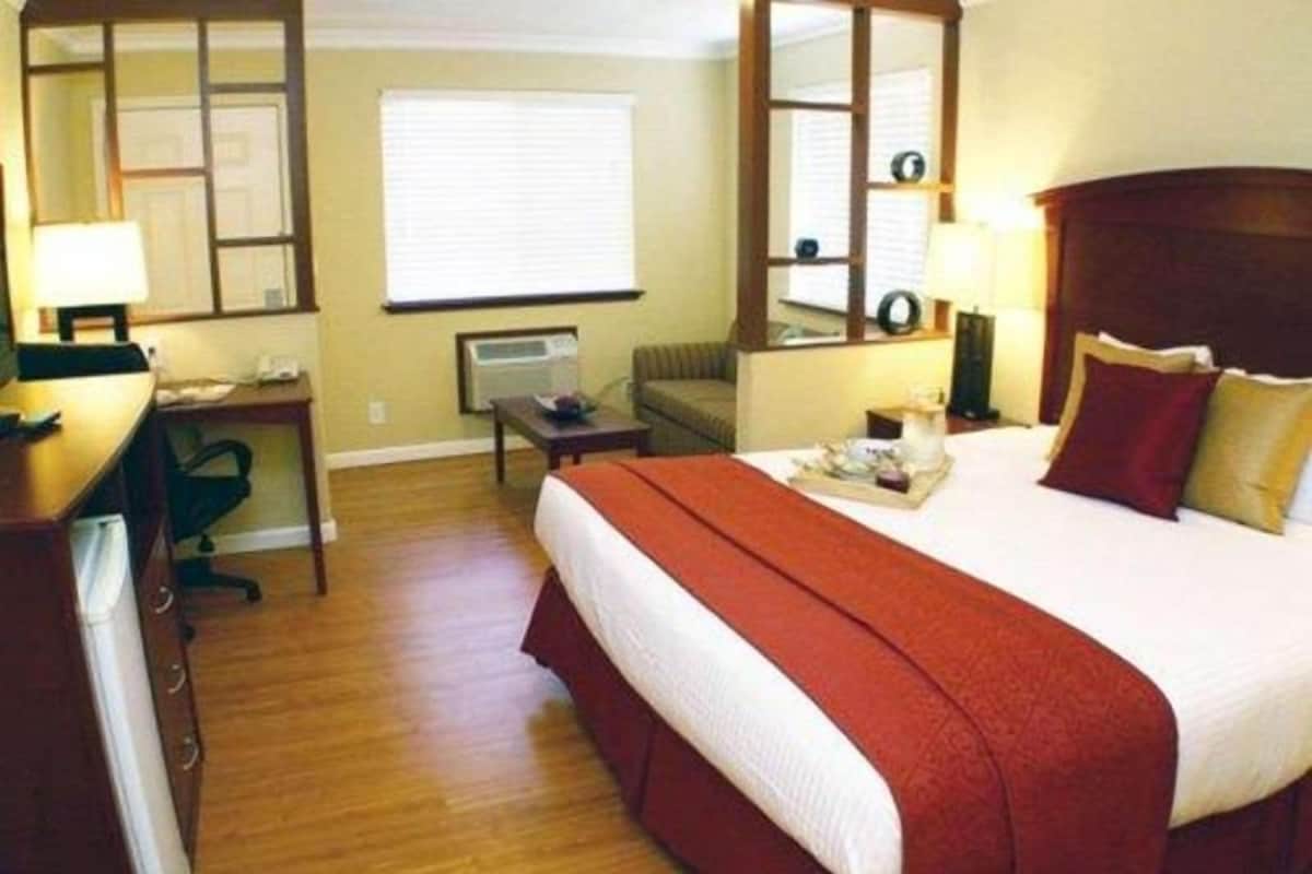 A hotel room with a bed, desk, chair, and a window.