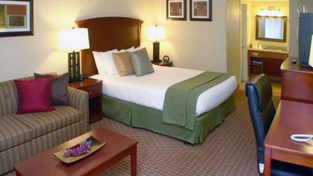 Ein Hotelzimmer mit Bett, einer Couch, einem Schreibtisch und einem Sessel.