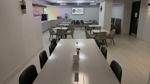 Une salle de conférence équipée d’une longue table, de chaises et d’un écran affichant le logo de la chaîne « Best Western ».