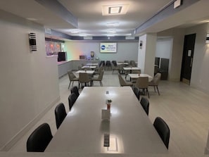 Une salle de conférence équipée d’une longue table, de chaises et d’un écran affichant le logo de la chaîne « Best Western ».
