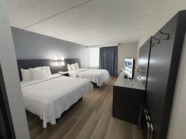 A hotel room with two beds, a desk, and a television.
