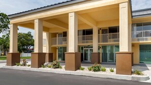 Hotel com entrada coberta, várias varandas e área frontal ajardinada.