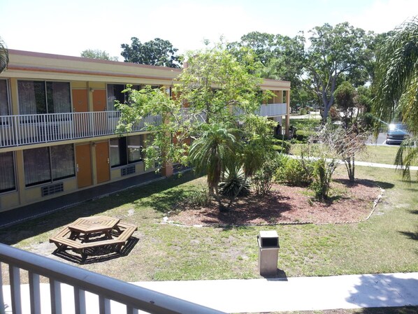 Un motel de dos pisos con un balcón y un pequeño patio amoblado con una mesa y sillas de madera.