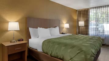 Ein Hotelzimmer mit einem Bett, zwei Nachttischlampen, einem Nachttisch mit Schublade und einem Vorhangfenster.