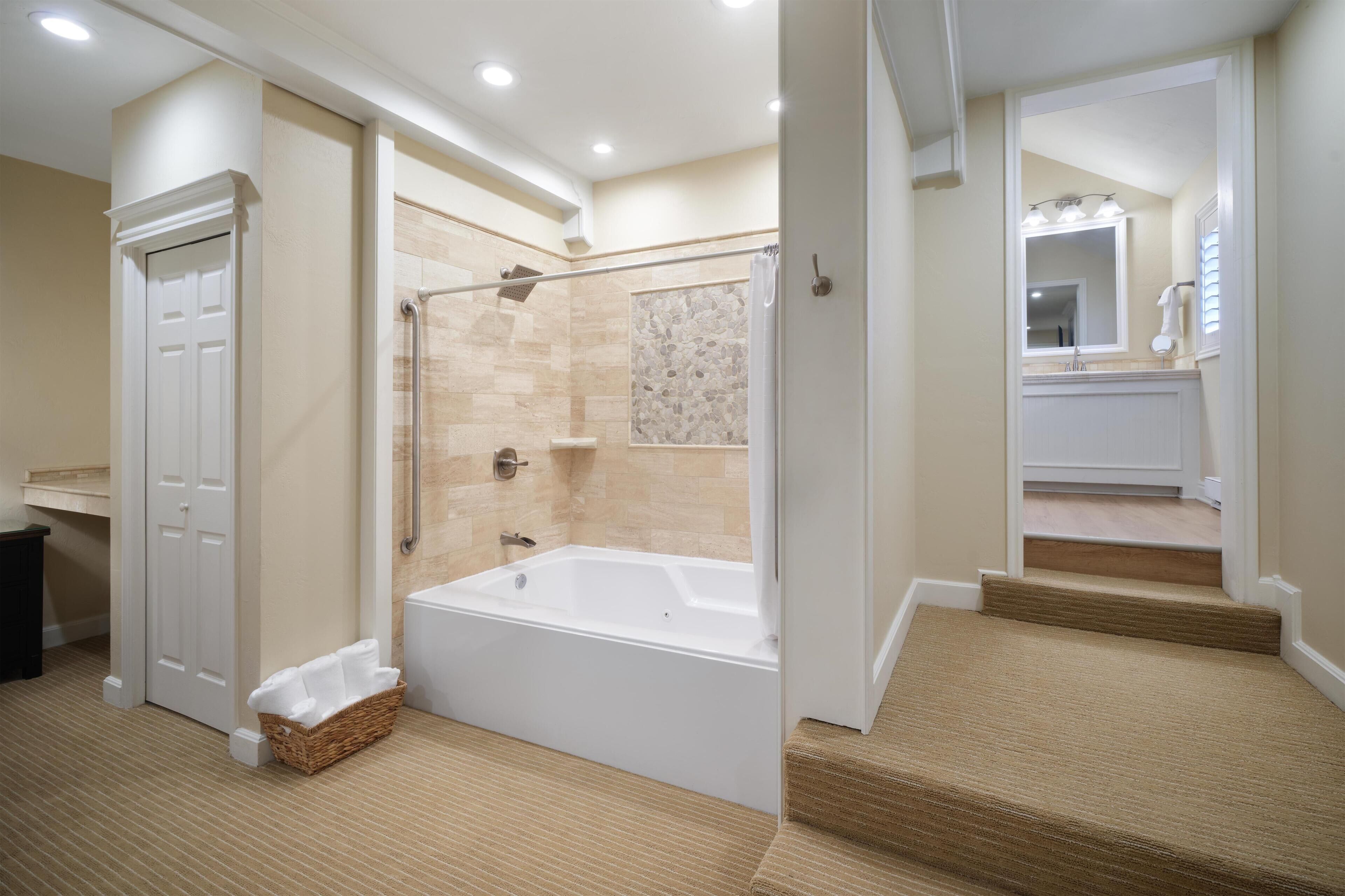 A spacious bathroom with a walk-in shower, a bathtub, and a vanity with a mirror.