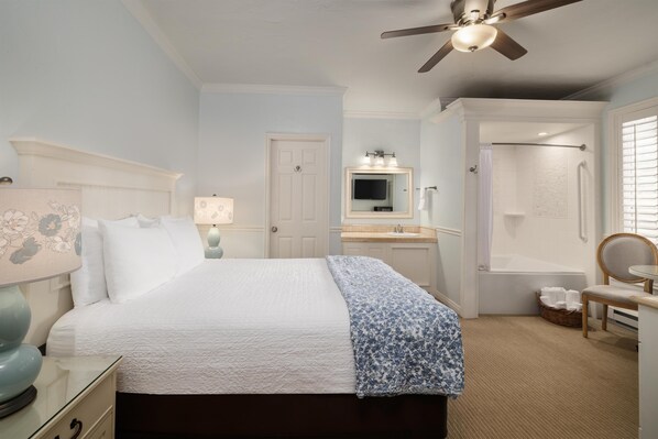 A bedroom with a bed, bedside table, lamp, ceiling fan, and a bathroom with a shower, toilet, and sink. - Best Western Grandma's Feather Bed (Juneau)
